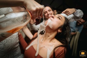 Champagne pours over a laughing wedding guest during a wild reception celebration at Som do Mar in Rio de Janeiro, Brazil